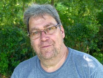 Stefan Fischer Porträtaufnahme mit Büschen im Hintergrund